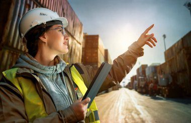 Beyaz şapkalı kadın endüstriyel mühendis konteyner terminalinde çalışıyor..