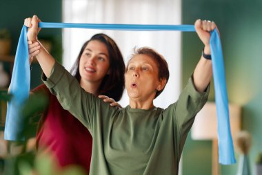 Kıdemli kadın egzersiz yapıyor. Evde fizik tedaviye yardım eden bir hemşire.