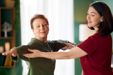 Kıdemli kadın egzersiz yapıyor. Evde fizik tedaviye yardım eden bir hemşire.