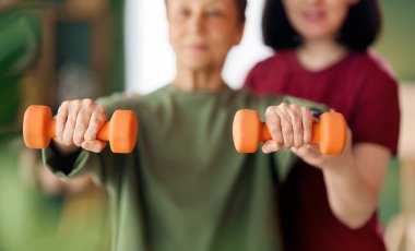 Kıdemli kadın halter egzersizi yapıyor. Evde fizik tedaviye yardım eden bir hemşire.