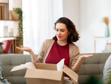 Kadın karton kutuları açıyor. Hayal kırıklığına uğramış online alışveriş kavramı.
