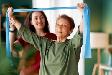 Kıdemli kadın egzersiz yapıyor. Evde fizik tedaviye yardım eden bir hemşire.