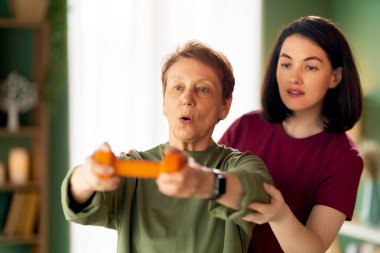 Kıdemli kadın halter egzersizi yapıyor. Evde fizik tedaviye yardım eden bir hemşire.