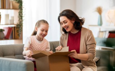 Anne ve kızı karton kutuları boşaltıyorlar. Çevrimiçi alışveriş kavramı.