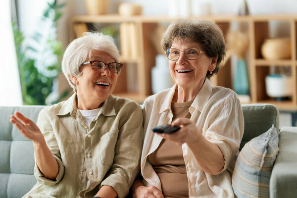 Senior women watching TV, movies. Retirees spending time at home.