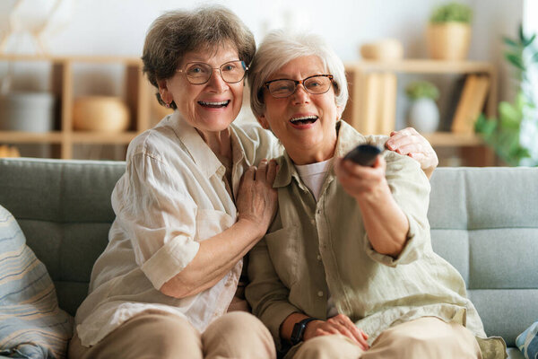 Senior women watching TV, movies. Retirees spending time at home.