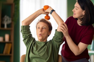 Kıdemli kadın halter egzersizi yapıyor. Evde fizik tedaviye yardım eden bir hemşire.