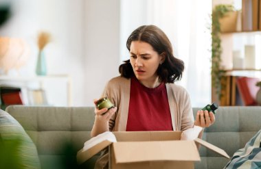 Kadın karton kutuları açıyor. Hayal kırıklığına uğramış online alışveriş kavramı.