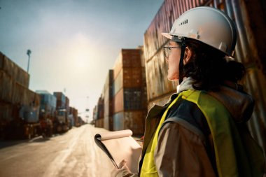 Beyaz şapkalı kadın endüstriyel mühendis konteyner terminalinde çalışıyor..