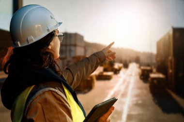 Beyaz şapkalı kadın endüstriyel mühendis konteyner terminalinde çalışıyor..