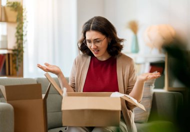 Kadın karton kutuları açıyor. Hayal kırıklığına uğramış online alışveriş kavramı.