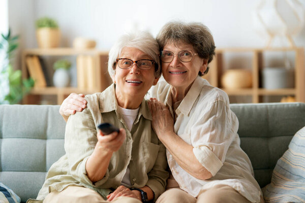 Senior women watching TV, movies. Retirees spending time at home.