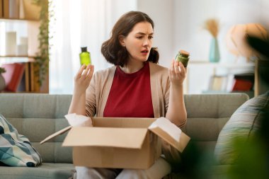 Kadın karton kutuları açıyor. Hayal kırıklığına uğramış online alışveriş kavramı.