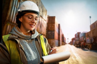 Beyaz şapkalı kadın endüstriyel mühendis konteyner terminalinde çalışıyor..