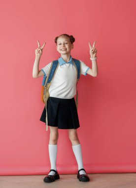 Parlak pembe arka planda duran sevimli mutlu ergen. Sırt çantalı çocuk, kız okula dönmeye hazır..