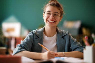 Okuldaki mutlu çocuk. Çocuk sınıfta öğreniyor ya da ev ödevi yapıyor.