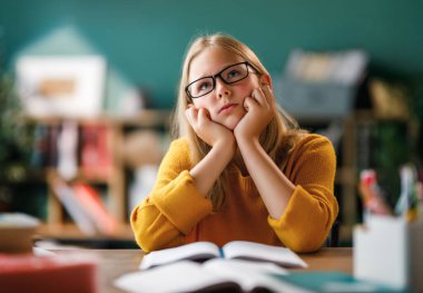 Okuldaki çocuk. Çocuk sınıfta öğreniyor ya da ev ödevi yapıyor.