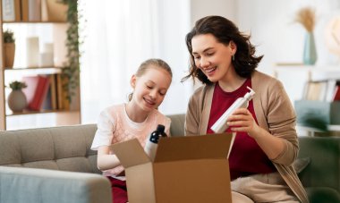 Anne ve kızı karton kutuları boşaltıyorlar. Çevrimiçi alışveriş kavramı.