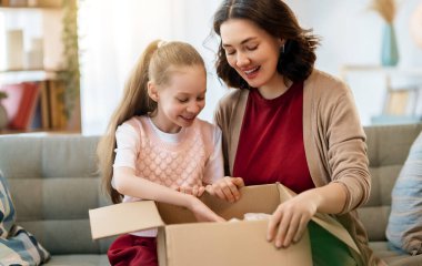 Anne ve kızı karton kutuları boşaltıyorlar. Çevrimiçi alışveriş kavramı.