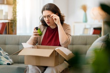 Kadın karton kutuları açıyor. Hayal kırıklığına uğramış online alışveriş kavramı.