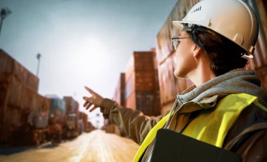 Beyaz şapkalı kadın endüstriyel mühendis konteyner terminalinde çalışıyor..