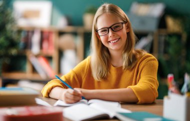 Okuldaki mutlu çocuk. Çocuk sınıfta öğreniyor ya da ev ödevi yapıyor.
