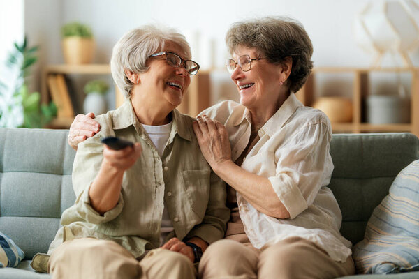 Senior women watching TV, movies. Retirees spending time at home.