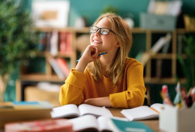 Okuldaki mutlu çocuk. Çocuk sınıfta öğreniyor ya da ev ödevi yapıyor.