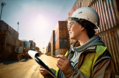 Beyaz şapkalı kadın endüstriyel mühendis konteyner terminalinde çalışıyor..