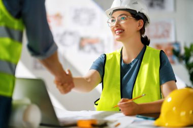 İnşaat alanında planlar üzerinde çalışan mimarlardan oluşan bir ekip..