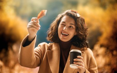 Bir sonbahar gününde sıcak çay içen rahat bir kadın.