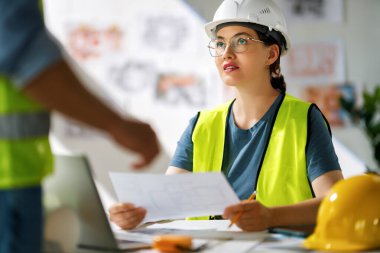 İnşaat alanında planlar üzerinde çalışan mimarlardan oluşan bir ekip..