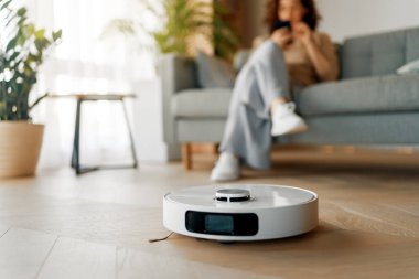 Ahşap zeminde beyaz robot elektrikli süpürge. Akıllı temizlik teknolojisi