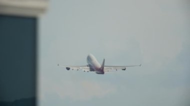 Long shot rear view of a huge double-deck airliner climbing after takeoff