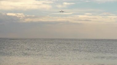 Unrecognizable plane flies over the sea. Passenger airliner landing down, front view