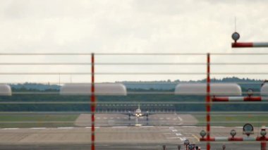 An unidentified turboprop aircraft descends to land at an airport in Europe. Front view through the landing lights on the runway
