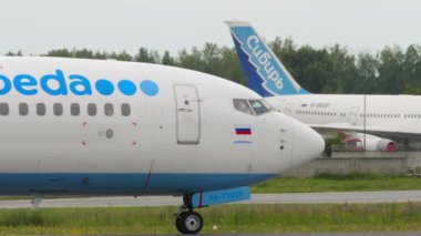 NOVOSIBIRSK, RUSSIAN FEDERATION - JULY 15, 2022: Side view of airplane Pobeda taxiing at Tolmachevo airport. Lowcost airline on the runway. Aircraft on the airfield. Tourism and travel concept