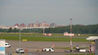 SAINT PETERSBURG, RUSSIA - JULY 26, 2022: Passenger plane of Rossiya taxiing on airfield of Pulkovo Airport. Tourism and travel concept. Panoramic view of the airport and infrastructure