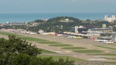 SOCHI, RUSSIA - JULY 29, 2022: Runway and busy traffic during the daytime, timelapse. Panoramic view of the airfield and the sea in the background. Tourism and travel concept