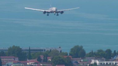 SOCHI, RUSSIA - AUGUST 03, 2022: Wide-body aircraft Boeing 777 of Aeroflot landing at Sochi airport, front view. Airliner in the blue sky over the sea. Tourism and travel concept