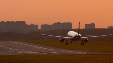 Cinematic footage of an airplane flying, landing at sunset, at dawn. Airfield illuminated by warm sunlight. Tourism and travel concept