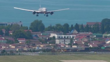 Widebody aircraft landing at Sochi airport, front view. Airliner in the blue sky over the sea. Tourism and travel concept