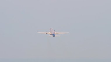 Long shot of an unrecognizable aircraft climbing after takeoff, view from the back. Tourism and travel concept