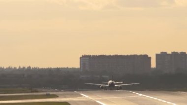Long shot, jet passenger plane accelerating and taking off. Rear view of a silhouette of an airliner flying away, climbing
