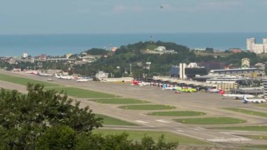 SOCHI, RUSSIA - JULY 29, 2022: Runway at the airport, timelapse traffic. Panoramic view of the airfield and the sea in the background. Tourism and travel concept