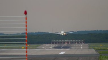 Passenger aircraft approaching before landing at Dusseldorf airport. View from the end of the runway