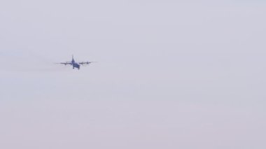 Four-engine turboprop cargo plane approaching to landing, long shot. Unrecognizable airplane silhouette in the sky