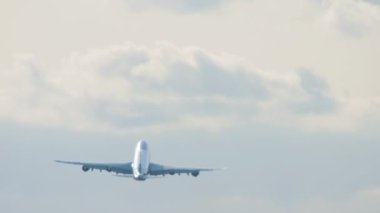 Wide body airplane fly away, long shot. Double-deck huge airliner climb after takeoff, rear view