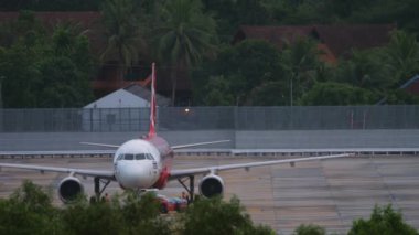 PHUKET, THAILAND - NOVEMBER 28, 2019: Passenger aircraft Airbus A320 of AirAsia on the airfield of Phuket airport. Tourism and travel concept