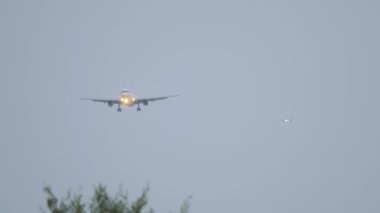Front view of jet airplane landing at dusk. Planes lined up in the sky. Tourism and travel concept